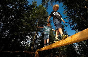 Kinder balanchieren über Holzbalken